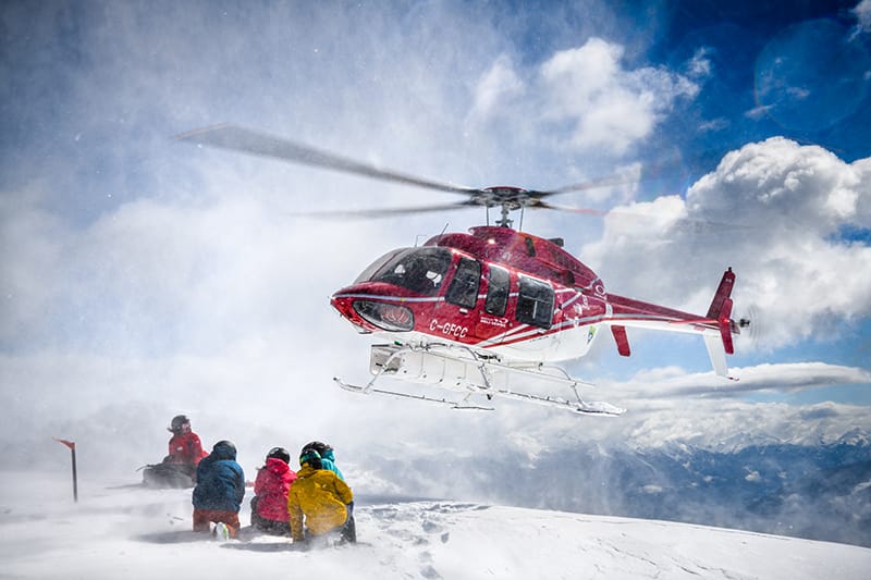 Helikopter auf einem zugeschneiten Berg in Lech-Zürs, der Skifahrer abholt