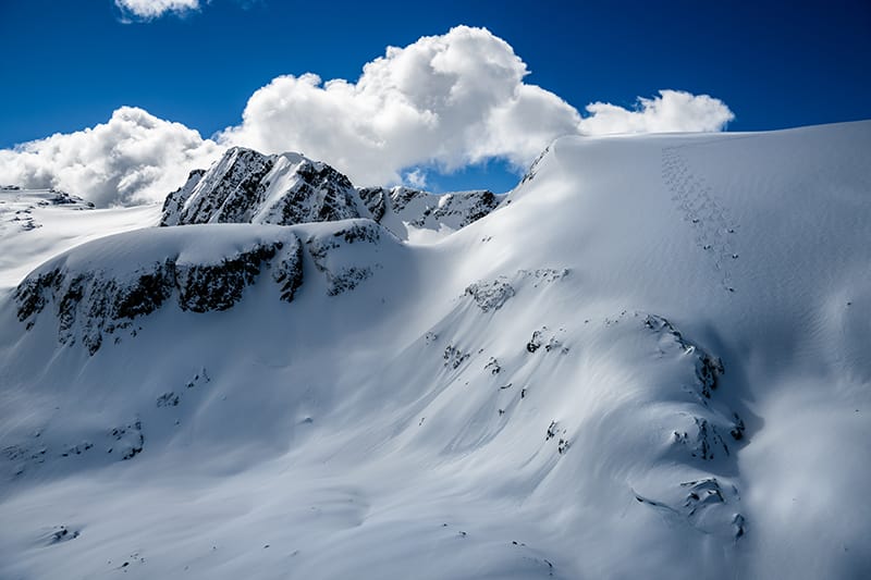 Helikopter auf einem zugeschneiten Berg in Lech-Zürs, der Skifahrer abholt